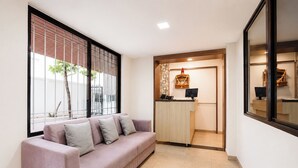 A reception area with a reception desk, a sofa, and a large window with blinds. - Fabhotel Ateethi Residency (Pune)