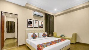 A hotel room with a bed, a bedside table, an air conditioning unit, a mirror, and a window with curtains. - FabHotel Runway, Near Jawahar Circle - Patrika Gate (Jaipur)