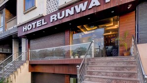 A hotel entrance with a sign reading 'HOTEL RUNWAY,' a staircase, and a glass door leading inside. - FabHotel Runway, Near Jawahar Circle - Patrika Gate (Jaipur)