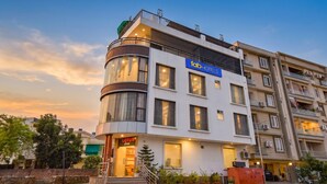 Un hotel moderno con una facciata a angolo curvo, diversi balconi e l'ingresso visibile del ristorante Lotus.