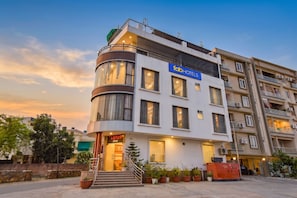 Ein modernes Hotel mit einer gebogenen Fassade, mehreren Balkonen und einem gut sichtbaren Eingang zum Lotus Restaurant.