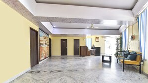 Un'ampia sala con pavimento in marmo, una reception, un divano e una ventola a soffitto.