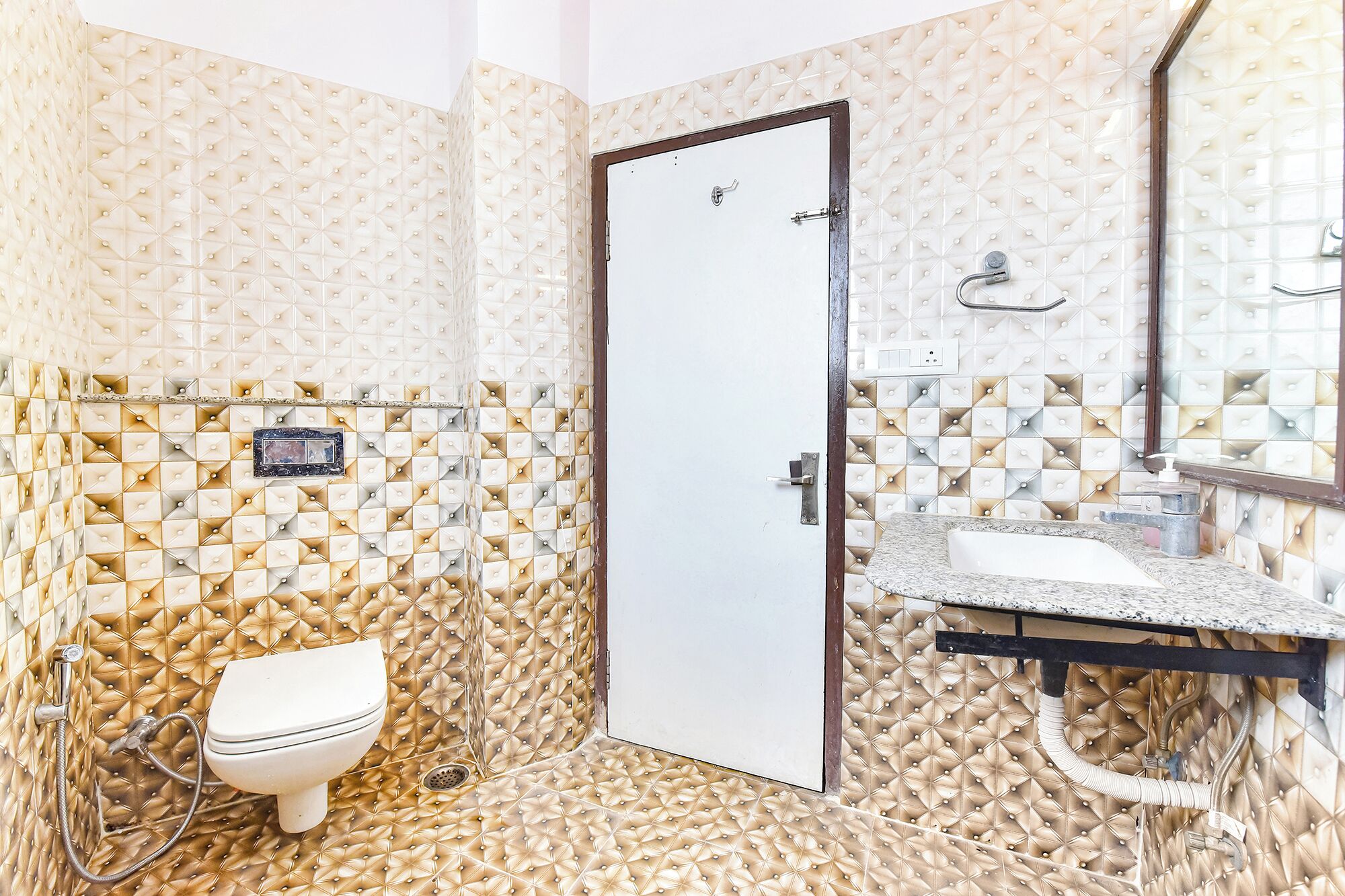 A bathroom with a white toilet, a sink with a mirror, and a door.