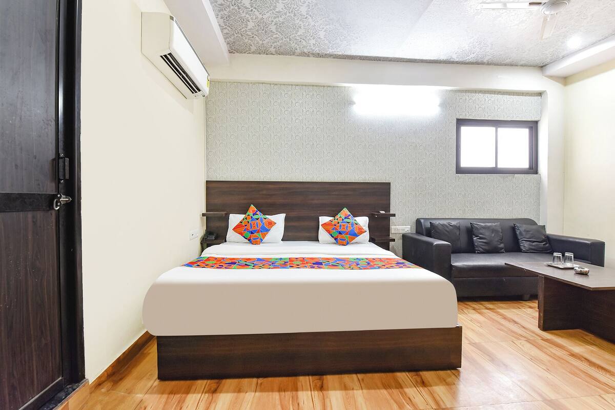 Habitación de hotel con cama, sofá, una mesita y ventana.