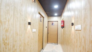 A hallway with wooden walls, a fire extinguisher, a door with a number sign, and a light switch. - Via The Akshardham Bliss - LAXMI NAGAR METRO (New Delhi)