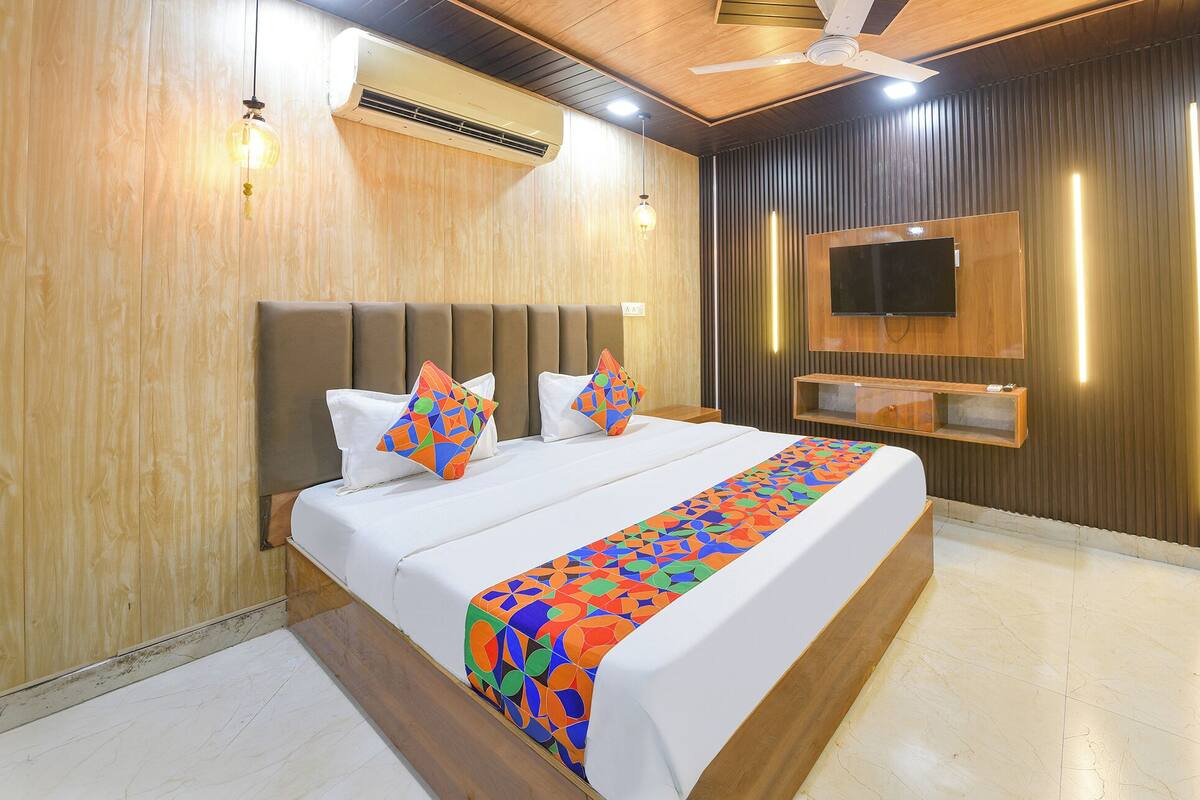 Quarto de hotel moderno com uma cama grande, televisão de tela plana na parede e ventoinha no teto.