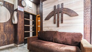 A room with a brown sofa, a wooden door, and a clock on the wall.