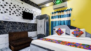 A hotel room with a bed, a brown armchair, a flat-screen TV, and a shower area.