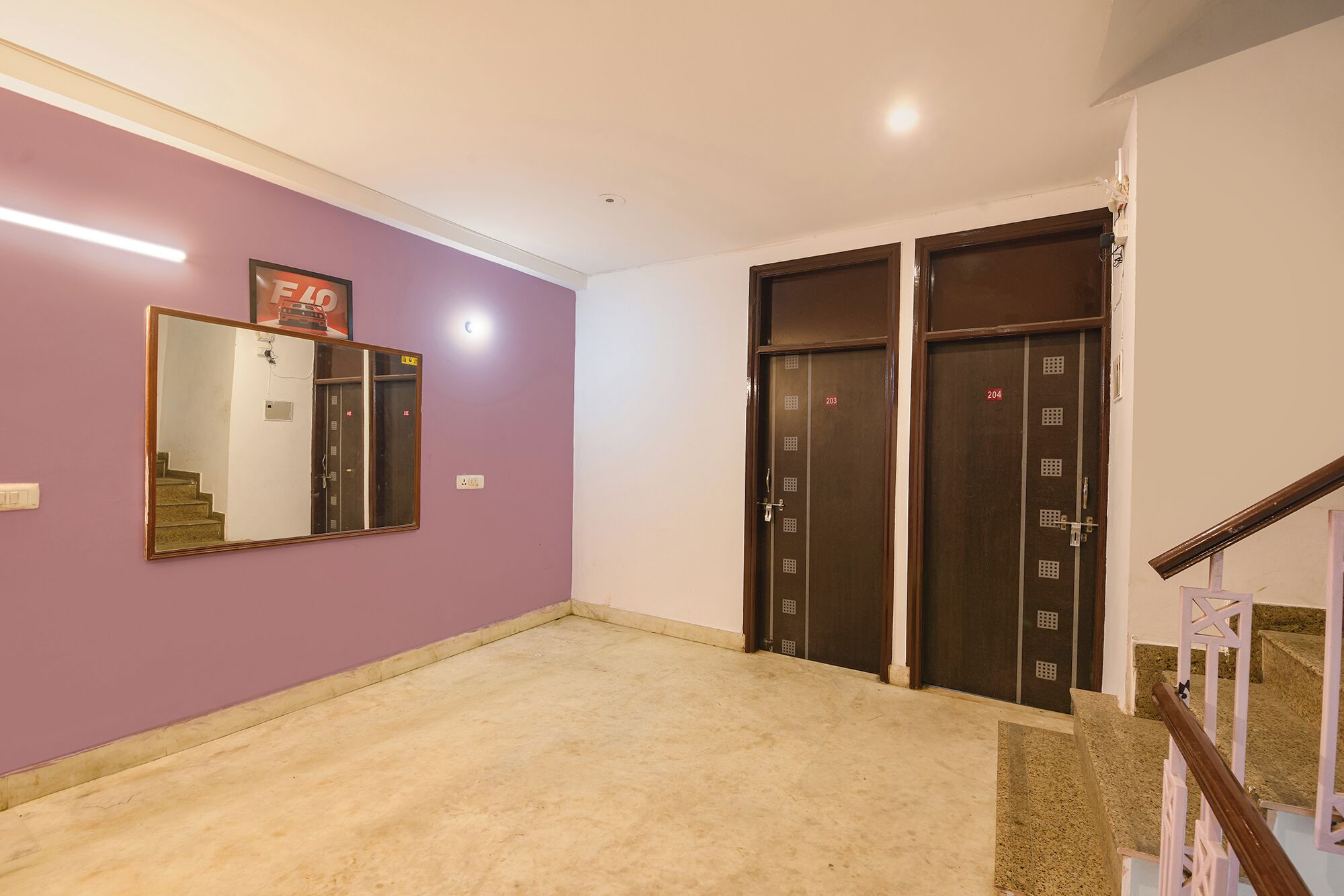 A hallway with purple walls, a mirror, two doors, and a staircase.