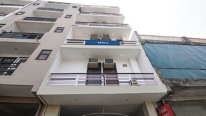 A multi-story building with balconies, a blue sign reading 'Via,' and a gated entrance. - Via A Square Residency (New Delhi)