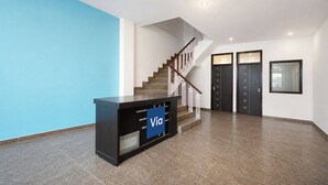 A modern interior with a staircase, a reception desk, and two doors. - Via A Square Residency (New Delhi)