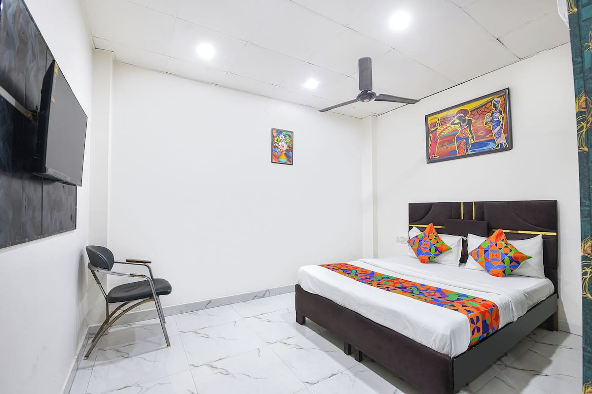 A bedroom with a bed, a chair, a ceiling fan, and artwork on the walls.