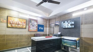 A reception desk with a computer, a fish tank, and framed artwork on the wall. - Via Vsr Stay (New Delhi)
