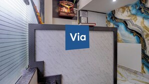 A reception area with a marble counter, a Via sign, a prayer wheel, and a mural. - Via Shera Residency (Mumbai)