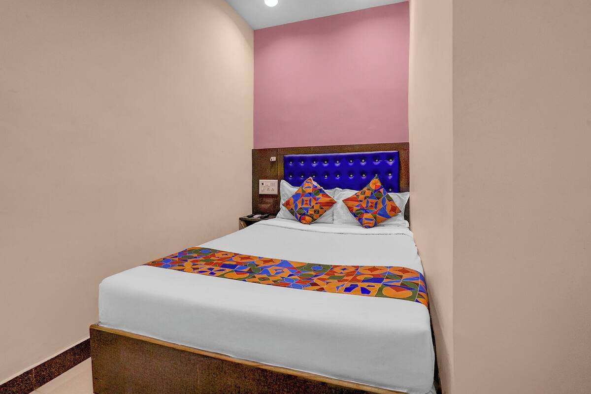 A neatly made bed with a patterned bedspread, a tufted headboard, and two decorative pillows.