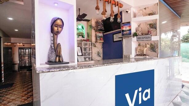 Una recepción con un cartel que dice 'Via', una estatua, un aviso de depósito de seguridad y una decoración de pavo real.