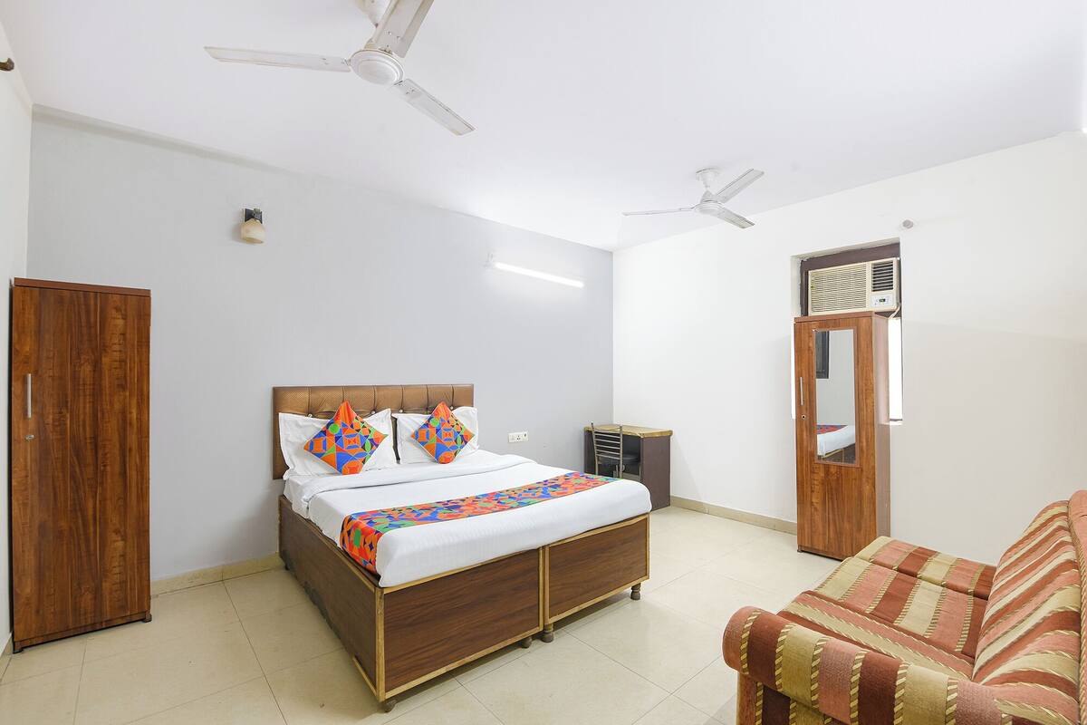 A bedroom with a wooden bed, two ceiling fans, a wardrobe, and a mirror.