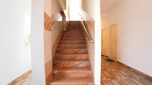 Una escalera de madera con barandilla de metal que lleva a una puerta al final.