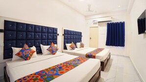 Habitación de hotel con dos camas, ventilador de techo, equipo de aire acondicionado y ventana con cortinas.