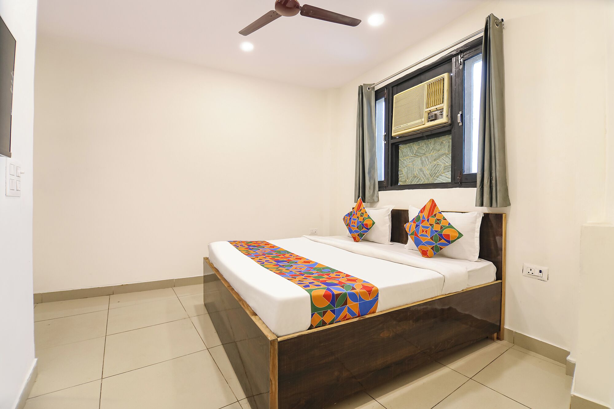 A bedroom with a bed, a ceiling fan, a window with curtains, and a radiator.