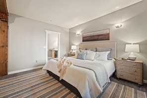 Une chambre à coucher avec un lit, des tables de chevet, une commode, une fenêtre et un tableau au mur.
