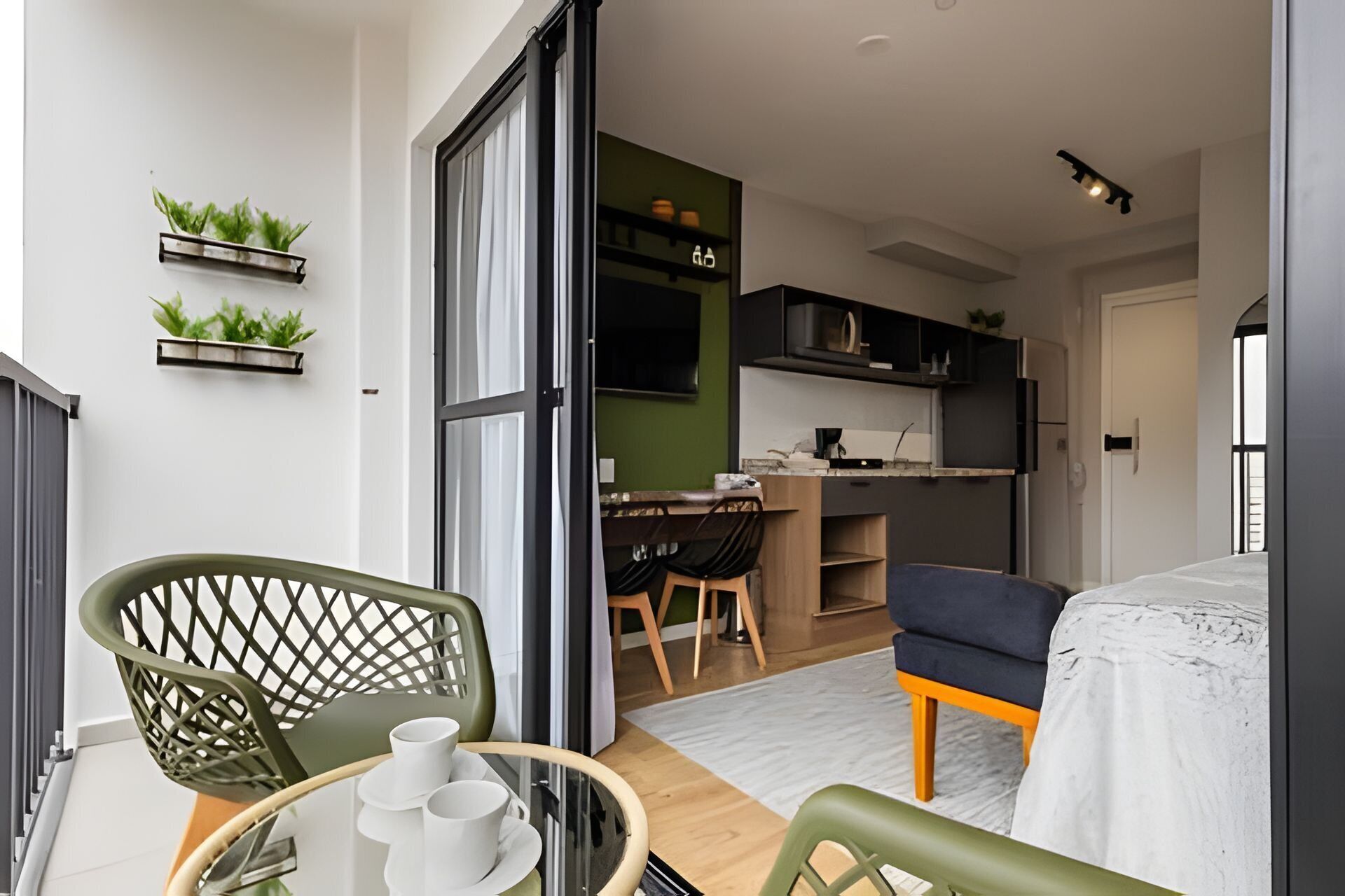 Um espaço compacto com área de refeições, cozinha compacta e varanda com cadeiras e mesa.