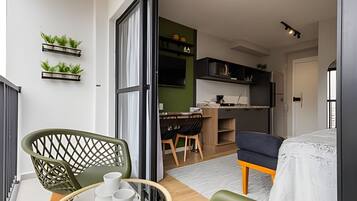 Um espaço compacto com área de refeições, cozinha compacta e varanda com cadeiras e mesa.