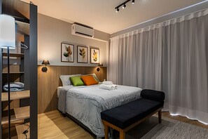 Ein modernes Schlafzimmer mit Bett, Sitzbank, Klimaanlage und Kunstwerk an der Wand.