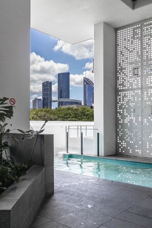 Ein moderner, überdachter Pool mit Blick auf die Stadt, einer Sichtschutzwand und einem Rauchverbot-Schild.