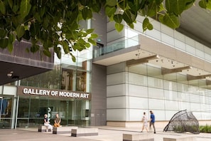 Ein modernes Gebäude mit Glasfassade und einem Schild, auf dem 'GALLERY OF MODERN ART' steht.