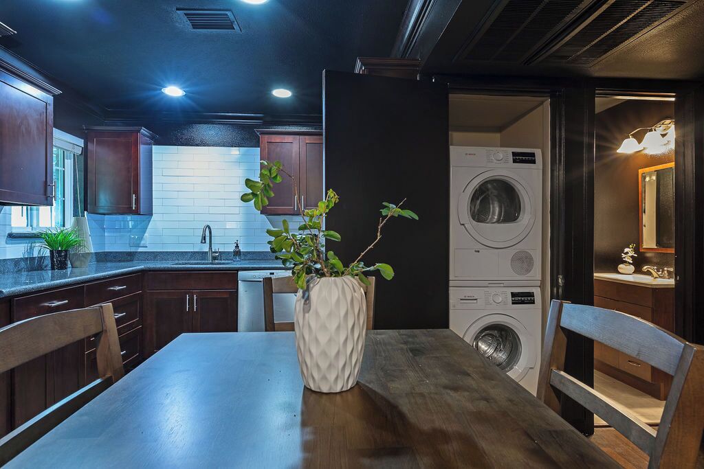 Een moderne keuken met donkere houten kastjes, een witte baksteen achterwand en een ingebouwde wasmachine.