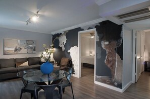 A modern living room with a glass coffee table, a sofa, and a decorative vase. - Your TMC Flats! Sleeps 32, 16BR, 8BA, 8PA (Houston)