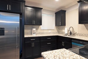 A kitchen with dark cabinets, a stainless steel refrigerator, a coffee maker, and a dishwasher. - Your TMC Flats! Sleeps 32, 16BR, 8BA, 8PA (Houston)