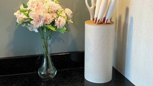 Eine Vase mit rosa Blumen und ein Behälter mit Scheren mit weißen Griffen.