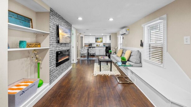 Una sala de estar moderna con chimenea, un comedor y una cocina al fondo.
