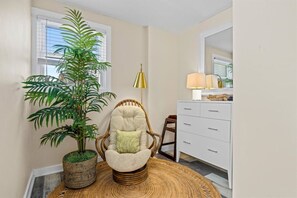 A room with a wicker chair, a potted plant, a lamp, and a white dresser. - Updated 6BR | 2.5 Blocks to Beach | Sleeps 13 (Ventnor City)