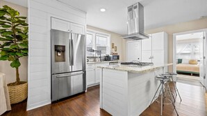 Una cocina moderna con armarios blancos, electrodomésticos de acero inoxidable y una isla central.