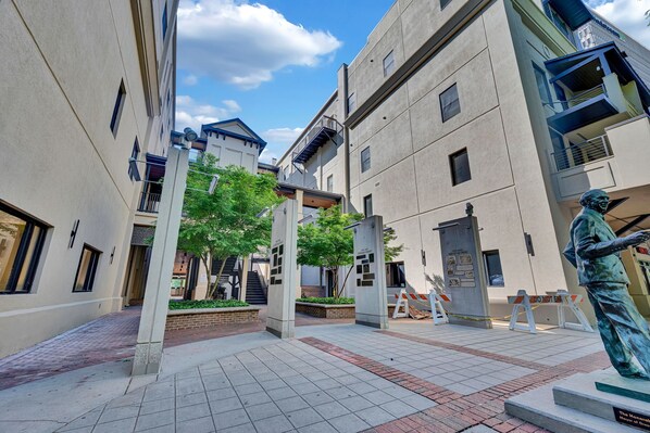 A courtyard with buildings, a statue, and a sign.
