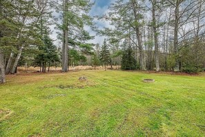 A grassy field with trees and a circular stone structure.