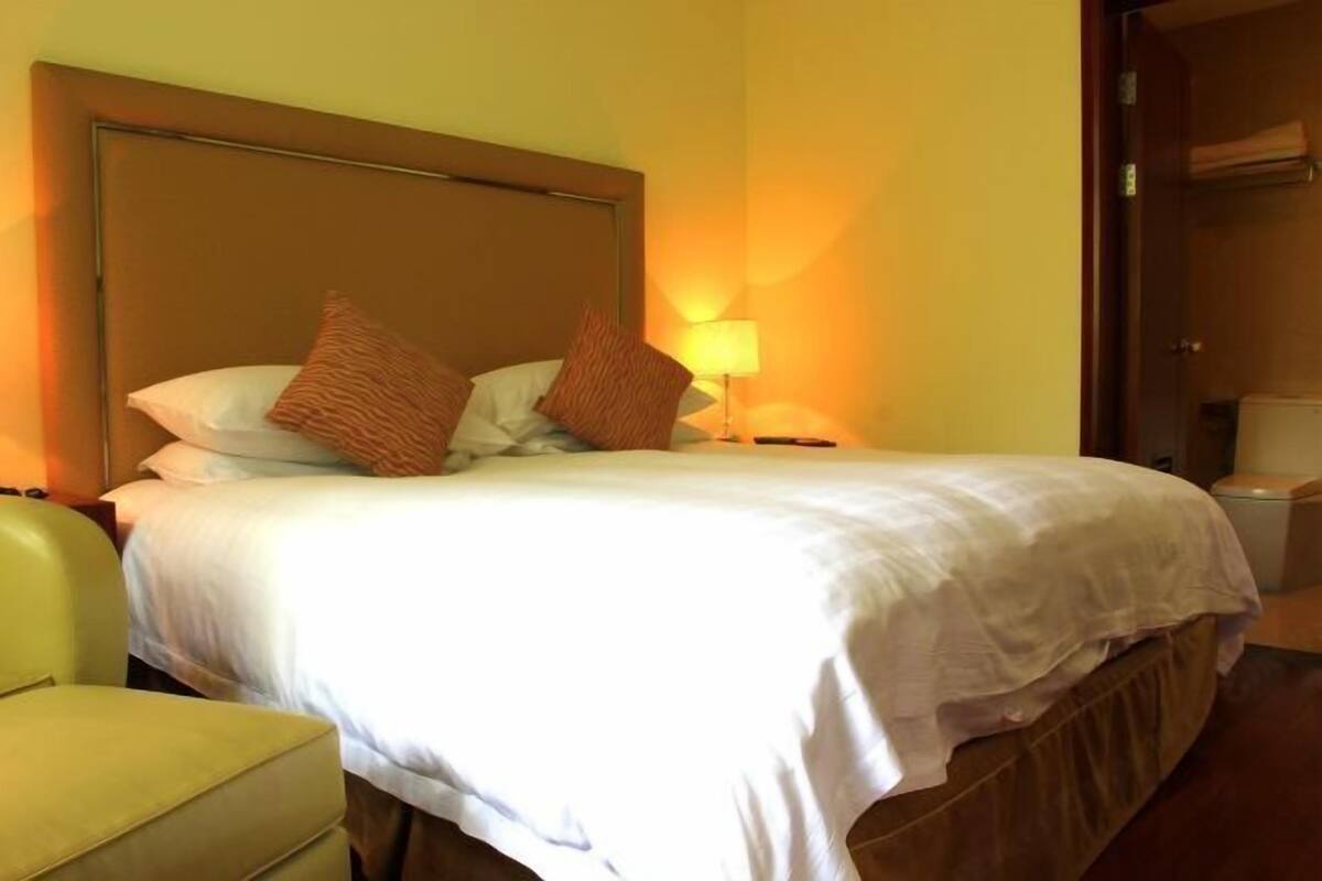 Una habitación de hotel con cama, mesita de noche, lámpara y una silla.