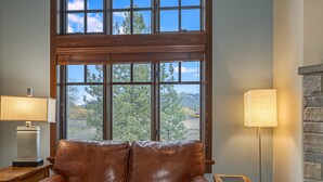 Una habitación con un sofá de cuero marrón, una lámpara y vistas amplias por las ventanas.
