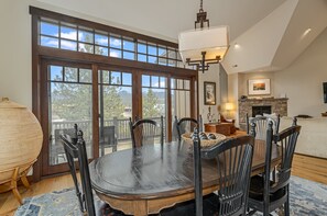 A dining area with a large table, chairs, and a view through the glass doors. - New! Cozy Craftsman Condo | Walk to Downtown Whitefish, Gas Fireplace & Mountain Views (Whitefish)