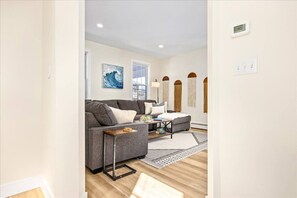 A modern living room with a grey sofa, a coffee table, and a patterned rug. - Modern 6BR | Sleeps 14 | 1.5 Blks to Beach (Ventnor City)