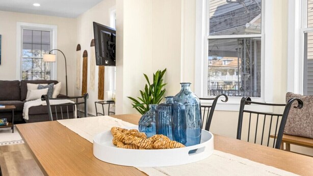 Zona pranzo con tavolo in legno, vasi di vetro blu e cesto di vimini.