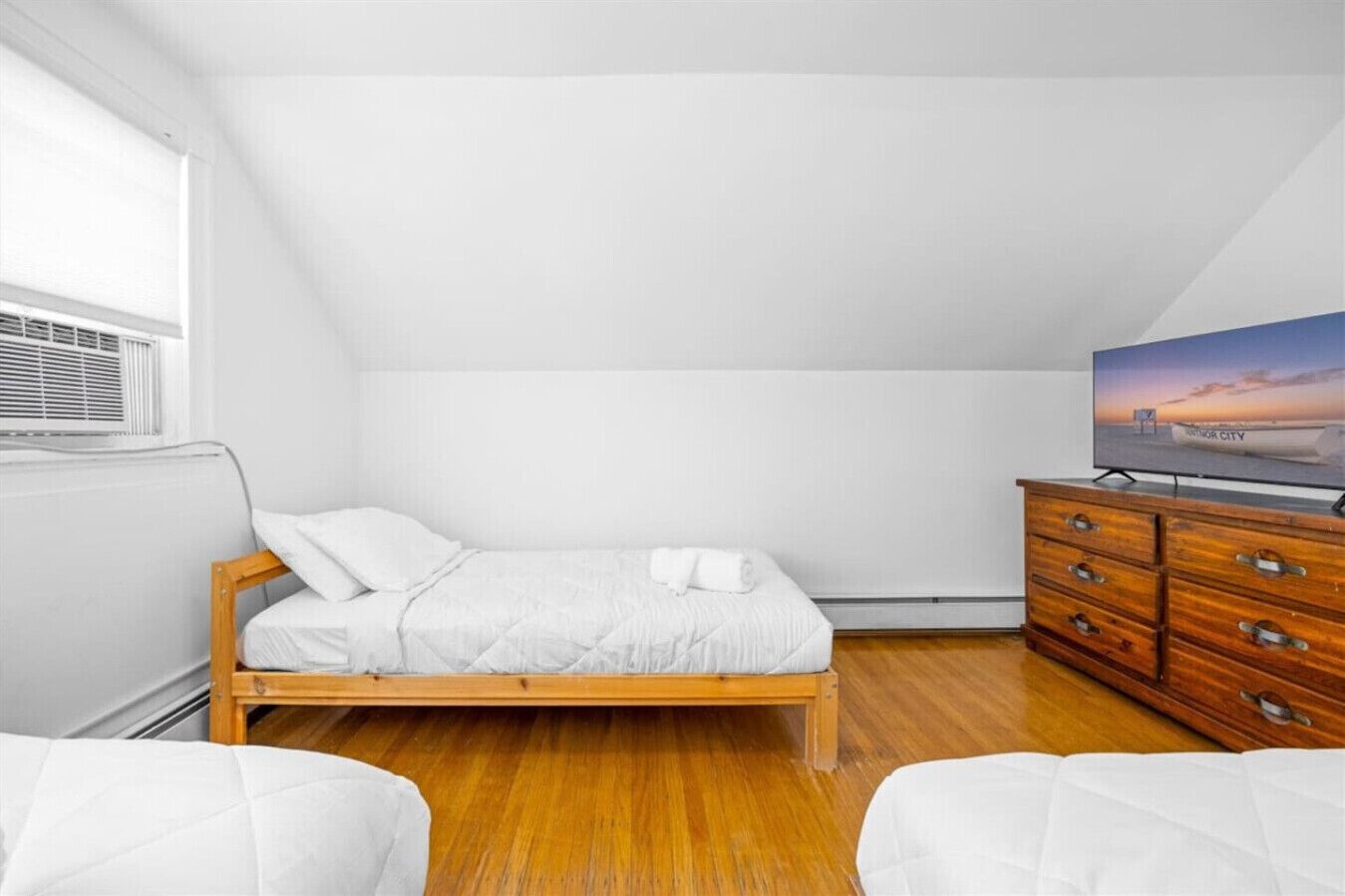 A bedroom with a bed, a dresser, and a television on a stand.