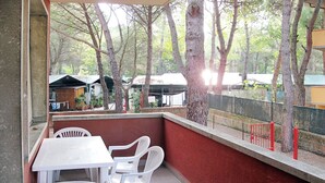 Une terrasse avec une table et des chaises, un mur rouge et des arbres en arrière-plan.