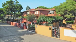 Un immeuble résidentiel à la façade rouge, doté d’une entrée sécurisée et surplombant un ciel dégagé.