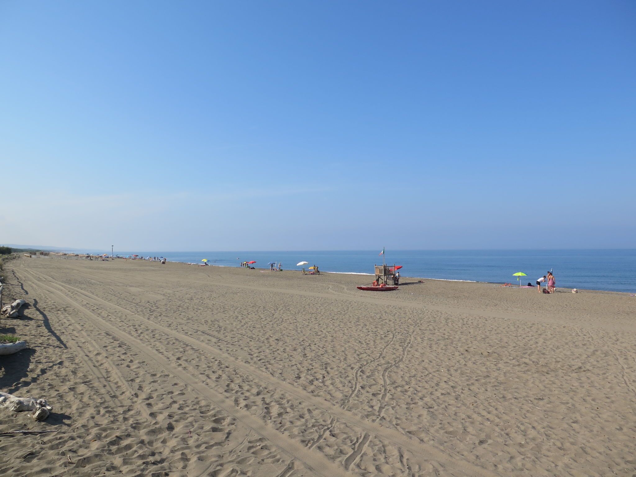 Una extensa playa de arena con un puesto de salvavidas y sombrillas.