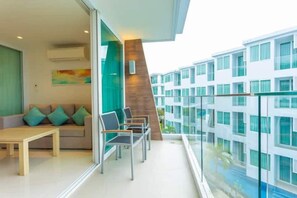 Una habitación de hotel moderna con balcón, sofá, mesa y vistas a otros edificios de hotel.