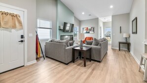 Un salon moderne comprenant un ensemble de canapés, un téléviseur et un coin repas avec une table et des chaises.